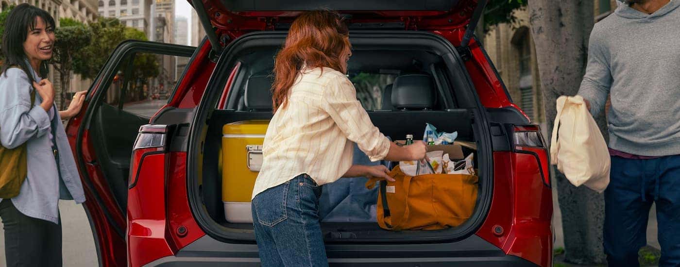 Woman grabbing groceries from the back of a red 2026 Chevy Equinox