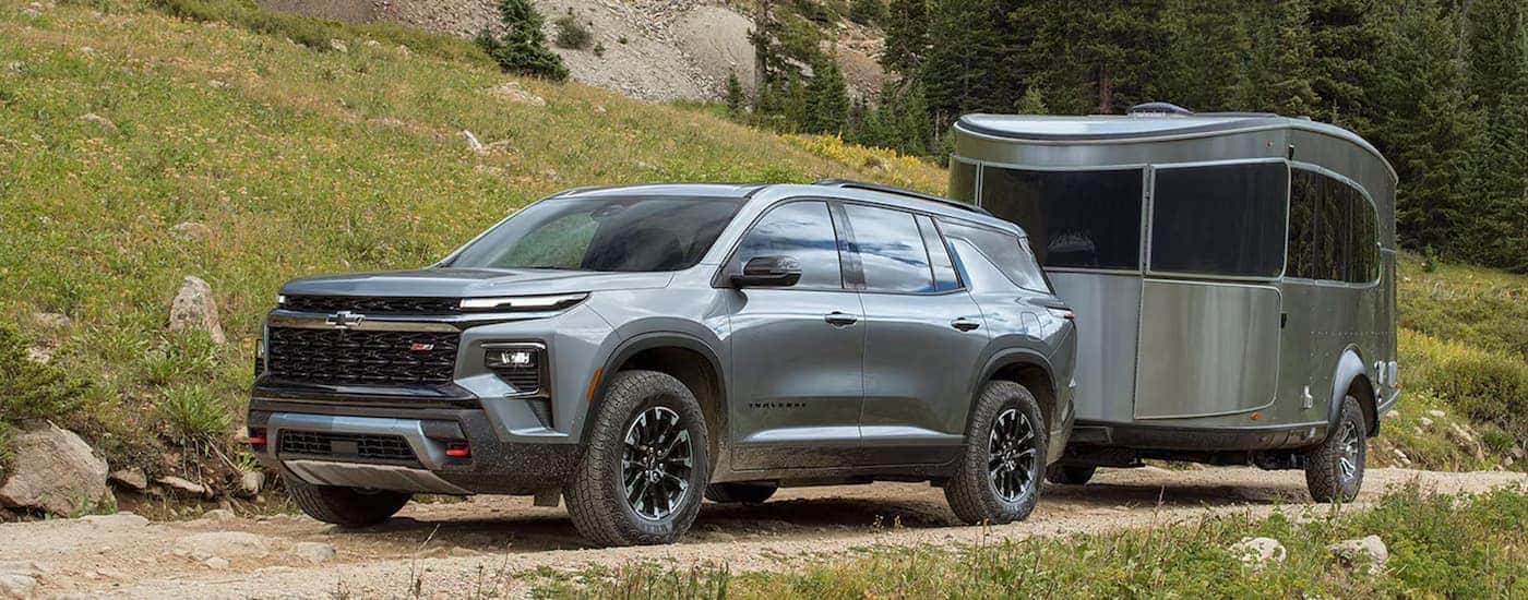 Silver 2026 Chevy Traverse towing a camper off-road.