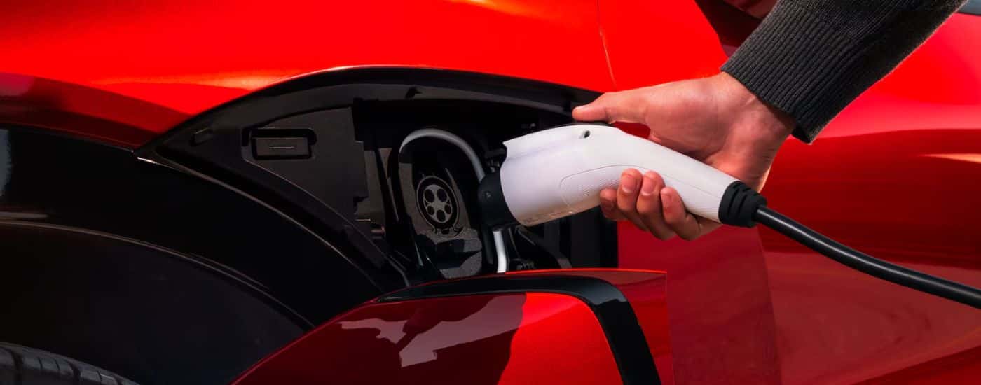 A red 2026 Chevy Blazer EV being plugged into a charger.