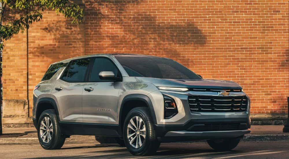 A silver 2026 Chevy Equinox parked in front of a brick wall.