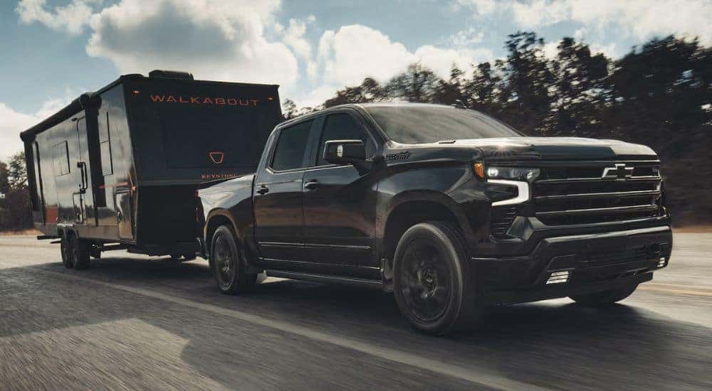 Black 2026 Chevy Silverado 1500 High Country towing a camper.