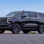 Black 2026 Chevy Suburban High Country parked near a beach.
