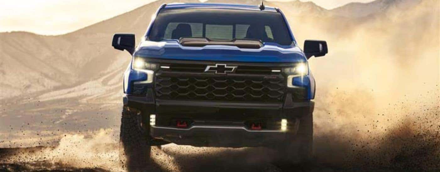 Blue 2026 Chevy Silverado 1500 ZR2 driving on a dusty terrain.