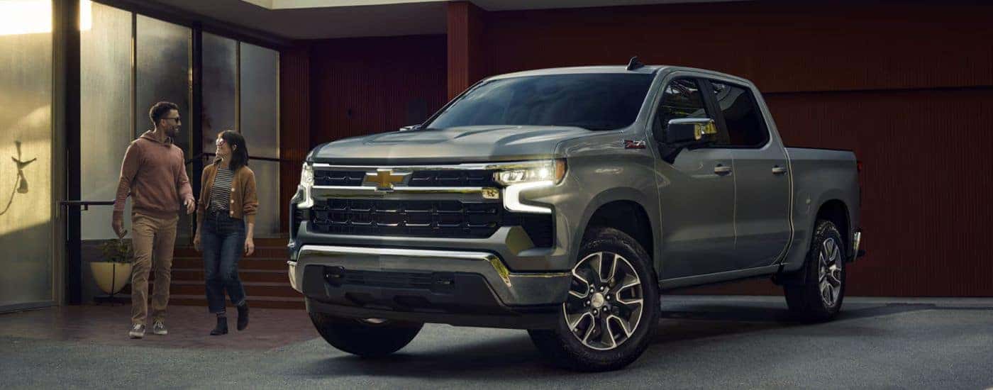 Grey 2026 Chevy Silverado 1500 parked in a driveway with a couple walking toward it.