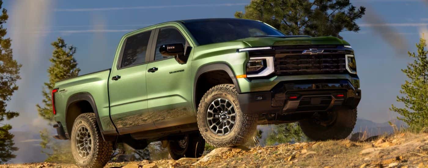 Green 2027 Chevy Silverado 1500 driving on an off-road dirt trail.