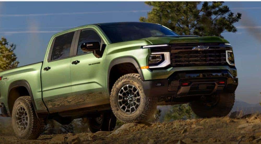 A green 2027 Chevy Silverado 1500 Trail Boss parked on rocky terrain.
