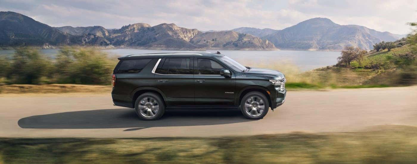 A black 2022 Chevy Tahoe High Country driving by a lake.