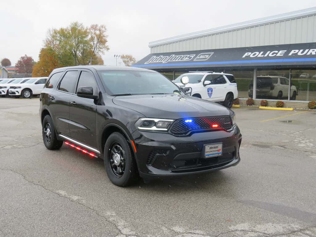 Front three-quarter view of a 2025 Dodge Durango patrol vehicle equipped with emergency lighting and driver-side spotlight.