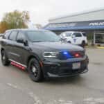 Front three-quarter view of a 2025 Dodge Durango patrol vehicle equipped with emergency lighting and driver-side spotlight.