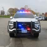 Front view of a white 2025 Chevrolet Tahoe police SUV with heavy-duty push bumper and spotlight.