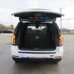 Rear angle of a white 2025 Chevrolet Tahoe police SUV with push bumper and rear flashers.