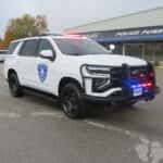 Front three-quarter view of a white 2025 Chevy Tahoe patrol vehicle with push bumper and LED warning lights.
