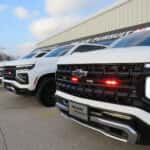 Three white 2025 Chevy Tahoe emergency response vehicles featuring roof-mounted light bars and reflective striping.
