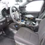 Interior view of a 2025 Dodge Durango police vehicle showing transport partition and mounted control console.