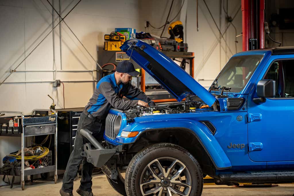 Technician servicing a blue Jeep Wrangler in the Juneau Jeep Ram service bay