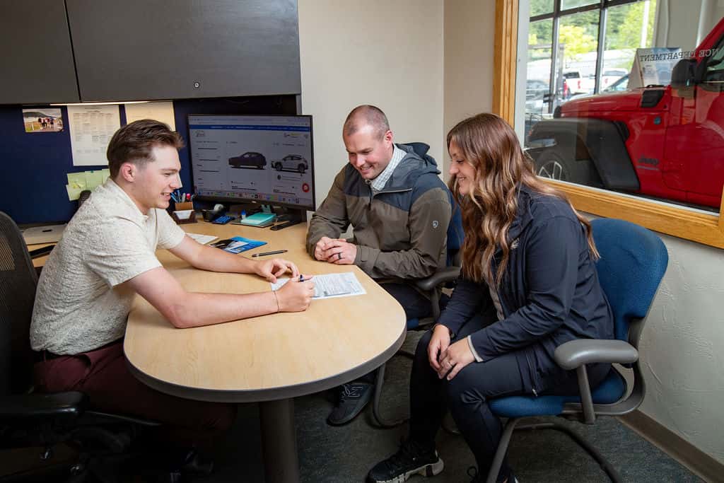 Juneau Jeep Ram finance team helping a couple review paperwork in the office