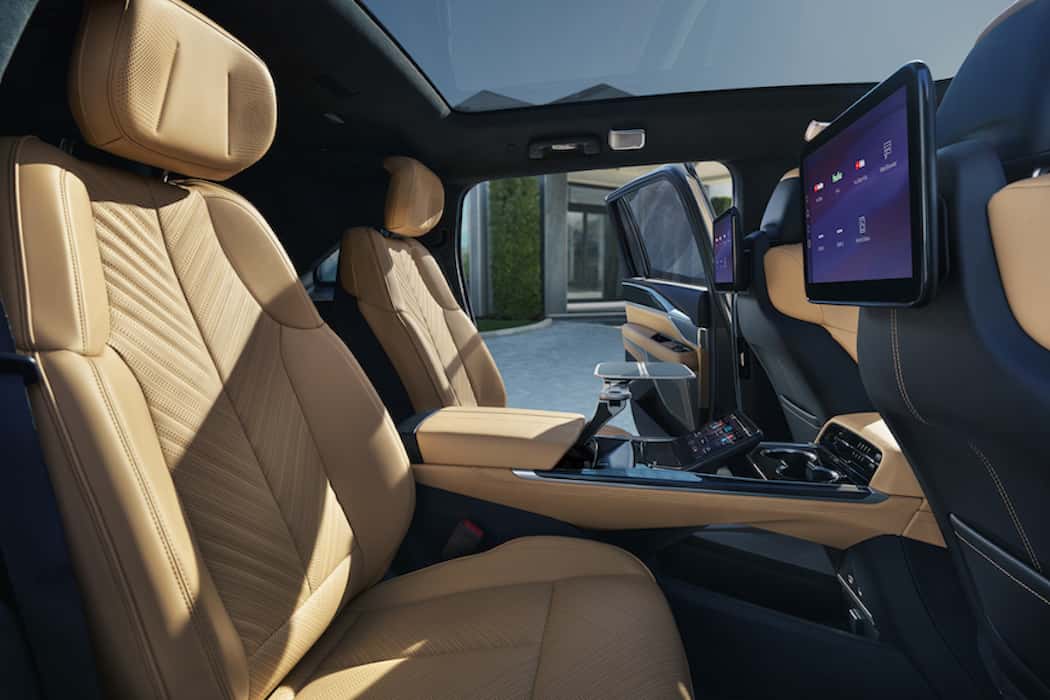 Cadillac 2026 ESCALADE IQ Sport 2 AWD with Executive 2nd Row Seating Package; Interior seen in Camelia Nouveauluxe with Backen Black accents; exterior seen in Flare Metallic; images show the 2nd Row Executive Seating Package, Tray Table, Rear Screen Infotainment Screens.