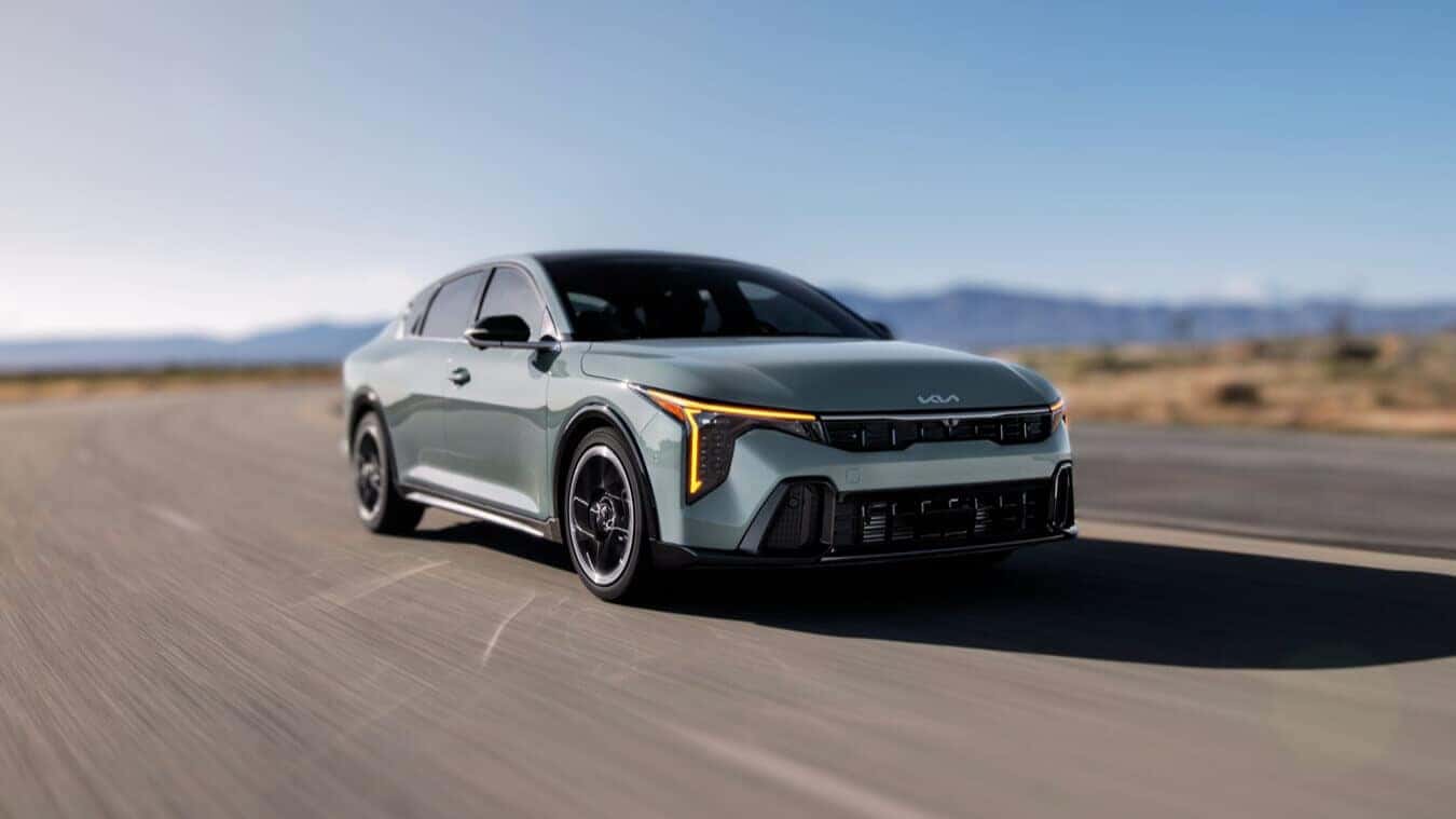 2025 Kia K4 in motion on an open road with a sleek, modern design and striking LED lighting