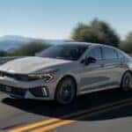 2025 wolf gray kia driving on a mountain road on a sunny day