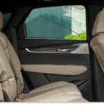 An interior view looking across the rear seats of a 2026 Cadillac XT5 featuring beige leather upholstery, dark door panels, and rear center console vents.