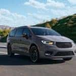 A grey 2024 Chrysler Pacifica is shown driving to a Chrysler dealer.