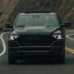 A black 2023 Ram 1500 is shown on a winding road after leaving a Ram dealer.