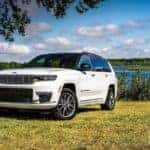 A white 2024 Jeep Grand Cherokee for sale is shown near a lake.