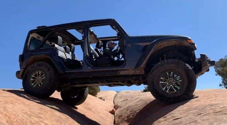 A grey 2024 Jeep Wrangler Rubicon is shown from the side while off-road.
