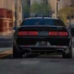A black 2023 Dodge Challeneger Black Ghost is shown driving on a city street.