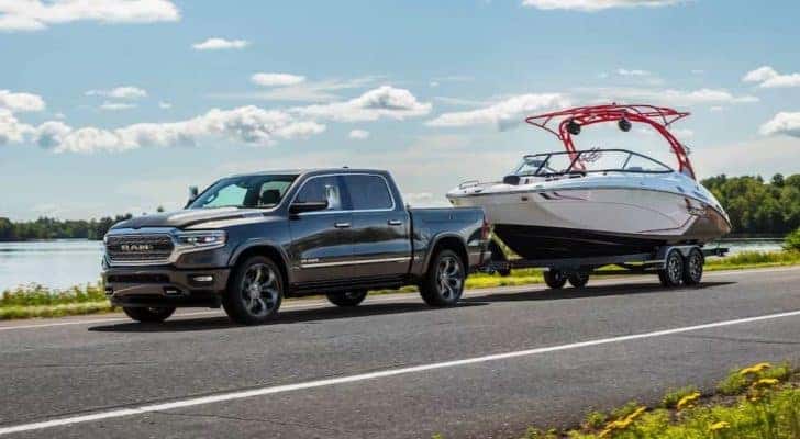 A gray 2024 Ram 1500 is shown towing a boat after visiting a Ram dealer near Concord.