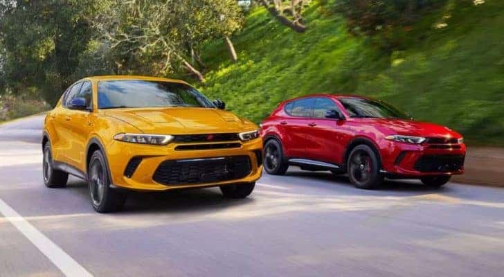 A yellow and a red 2024 Dodge Hornet are shown driving side-by-side after leaving a Dodge dealer.