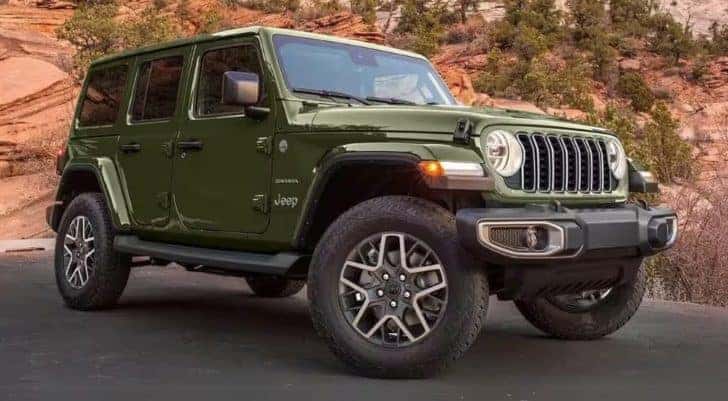 A green 2024 Jeep Wrangler Sahara is shown parked near a rocky hill.