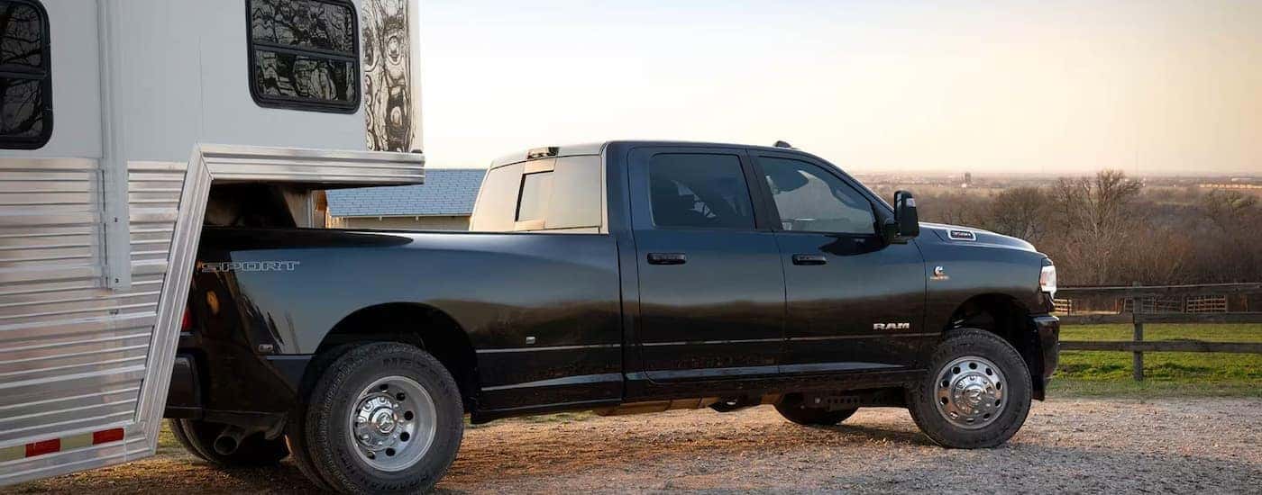 A black 2024 Ram 3500 for sale near Concord is hooked up to a large white trailer.