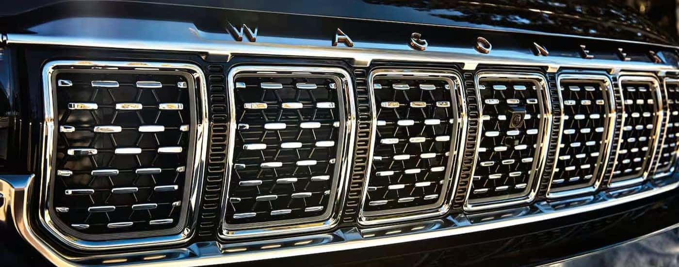 A close-up of a chrome grill is shown on a black 2025 Jeep Grand Wagoneer.