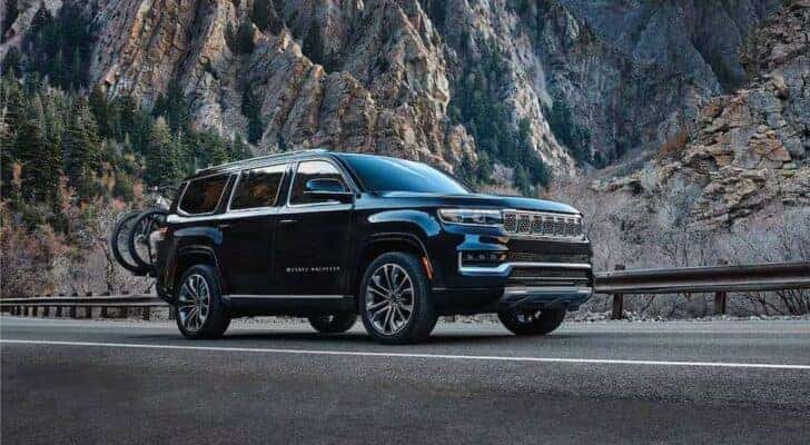 A black 2025 Jeep Grand Wagoneer for sale is shown driving on a highway.
