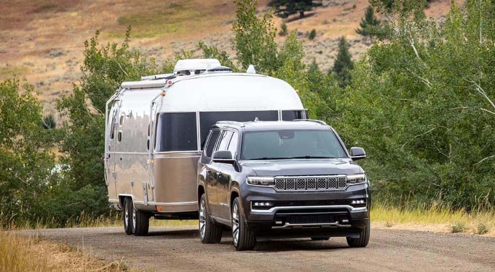 A black 2025 Jeep Grand Wagoneer towing an AirStream trailer.