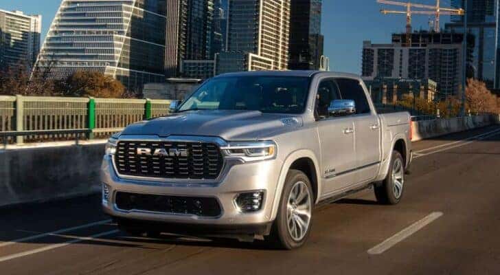 A grey 2025 Ram 1500 driving through a city.