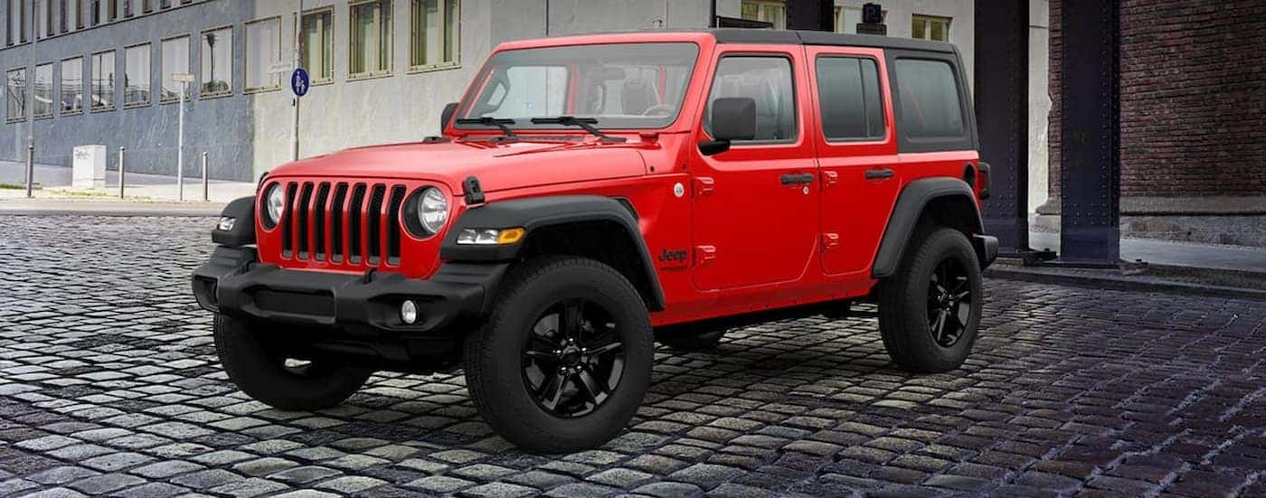 A red 2021 Jeep Wrangler parked near a city building.