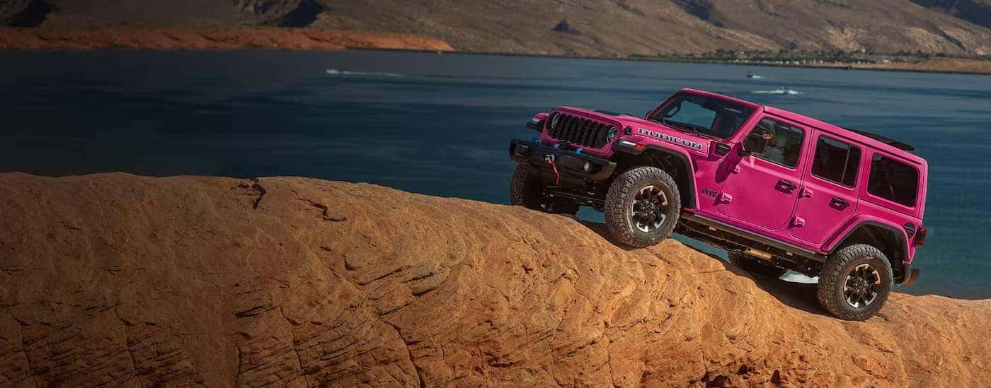 A pink 2024 Jeep Wrangler Rubicon off-roading.
