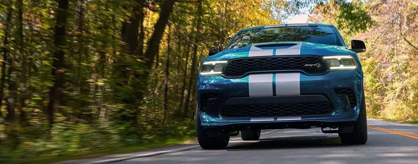A blue 2024 Dodge Durango SRT Hellcat driving down a forest road.