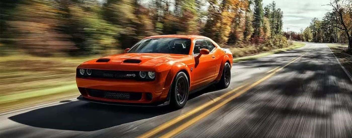An orange 2023 Dodge Challenger SRT driving to a Dodge dealer near Statesville.