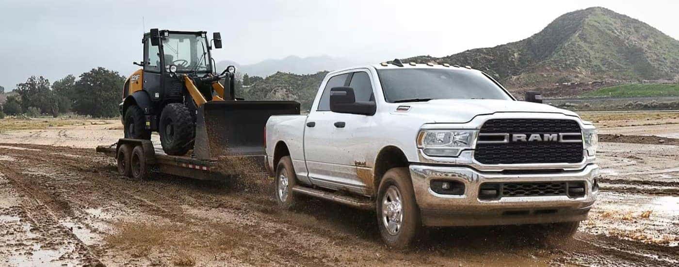 A white 2023 Ram 2500 towing a trailer off-road.