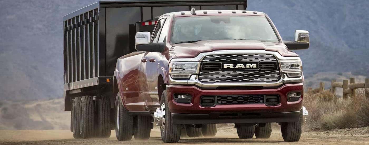 A maroon 2024 Ram 3500 towing a trailer behind it