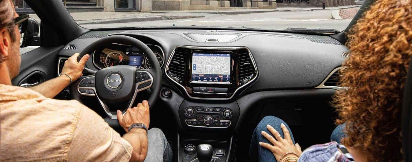 Couple in a used 2022 Jeep Cherokee driving down the street