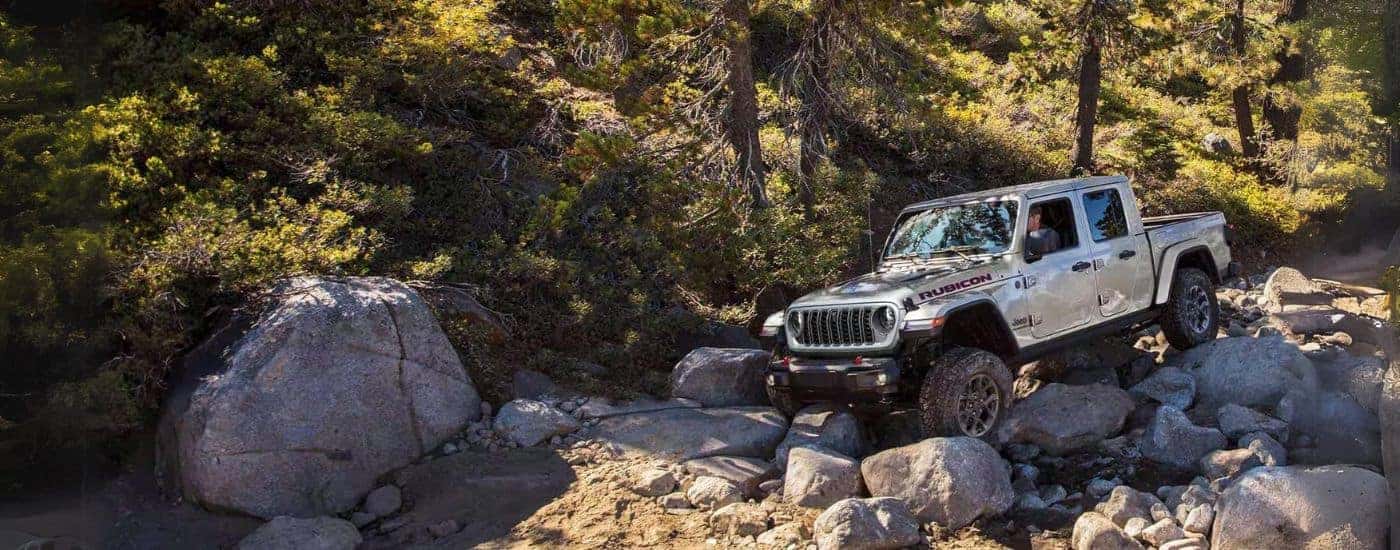White 2024 Jeep Gladiator Rubicon driving down rocks.