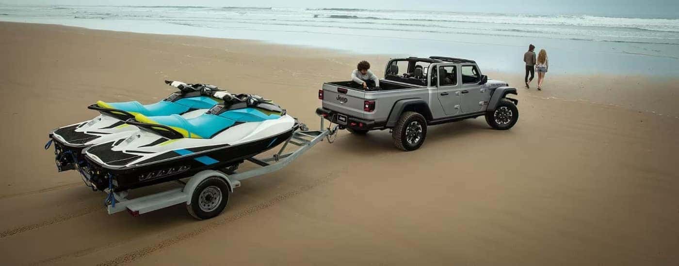 A grey 2024 Jeep Gladiator for sale in Cornelius towing jetskis.