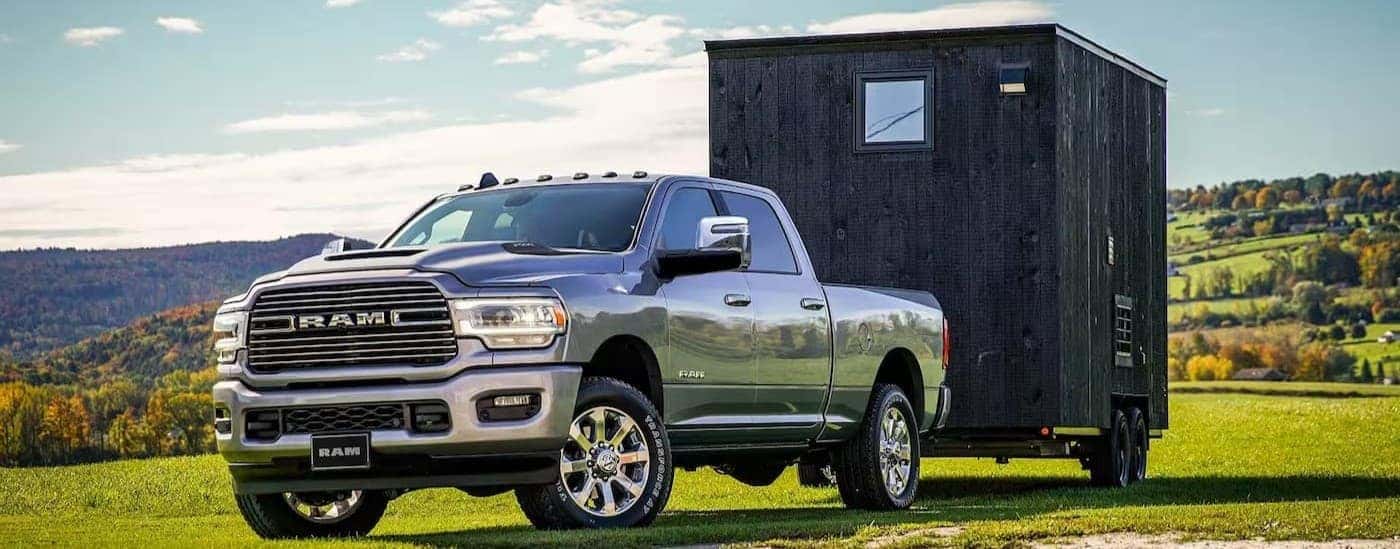 A silver 2024 Ram 2500 towing a trailer on grass.
