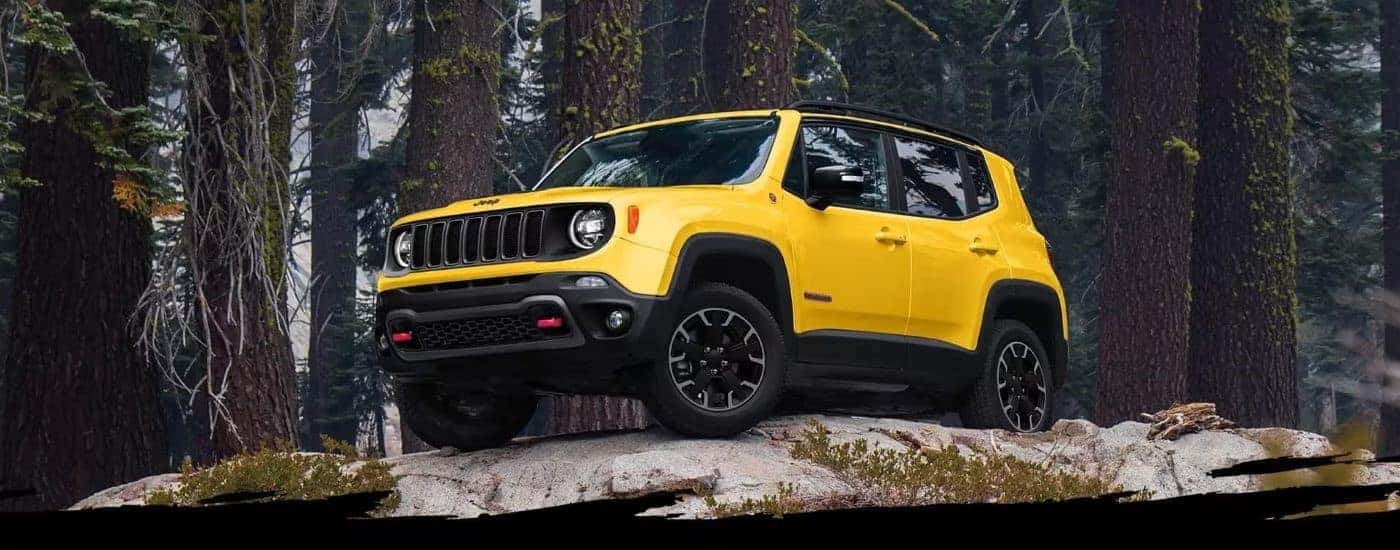Yellow 2023 Jeep Renegade driving off-road in a forest