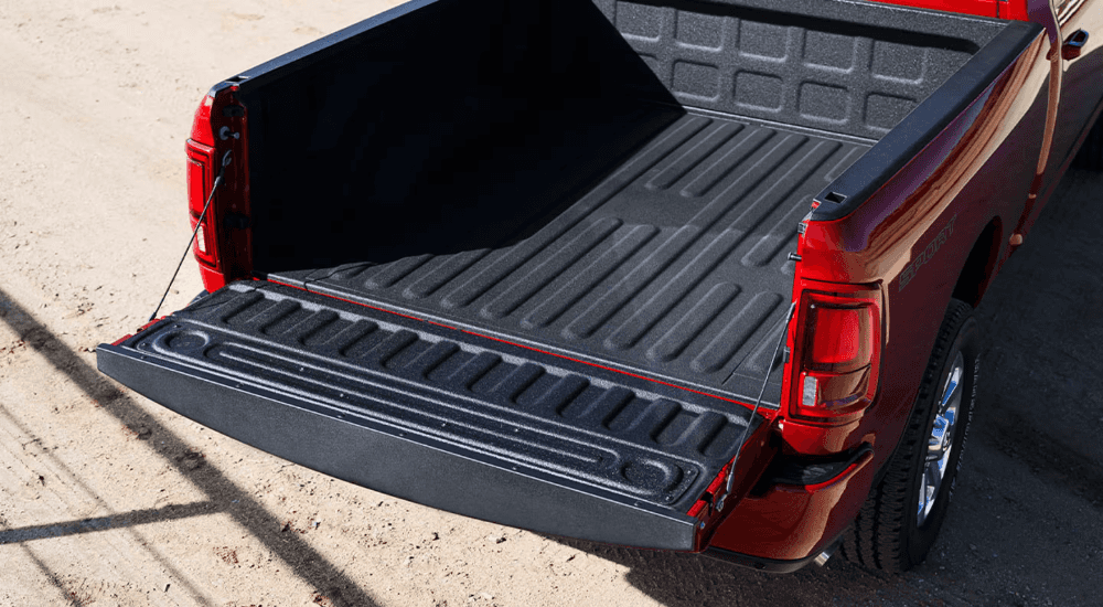 Bed of a red 2026 Ram 2500 at a dealership with work trucks for sale