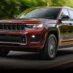 Maroon 2023 Jeep Grand Cherokee driving to a used car dealer